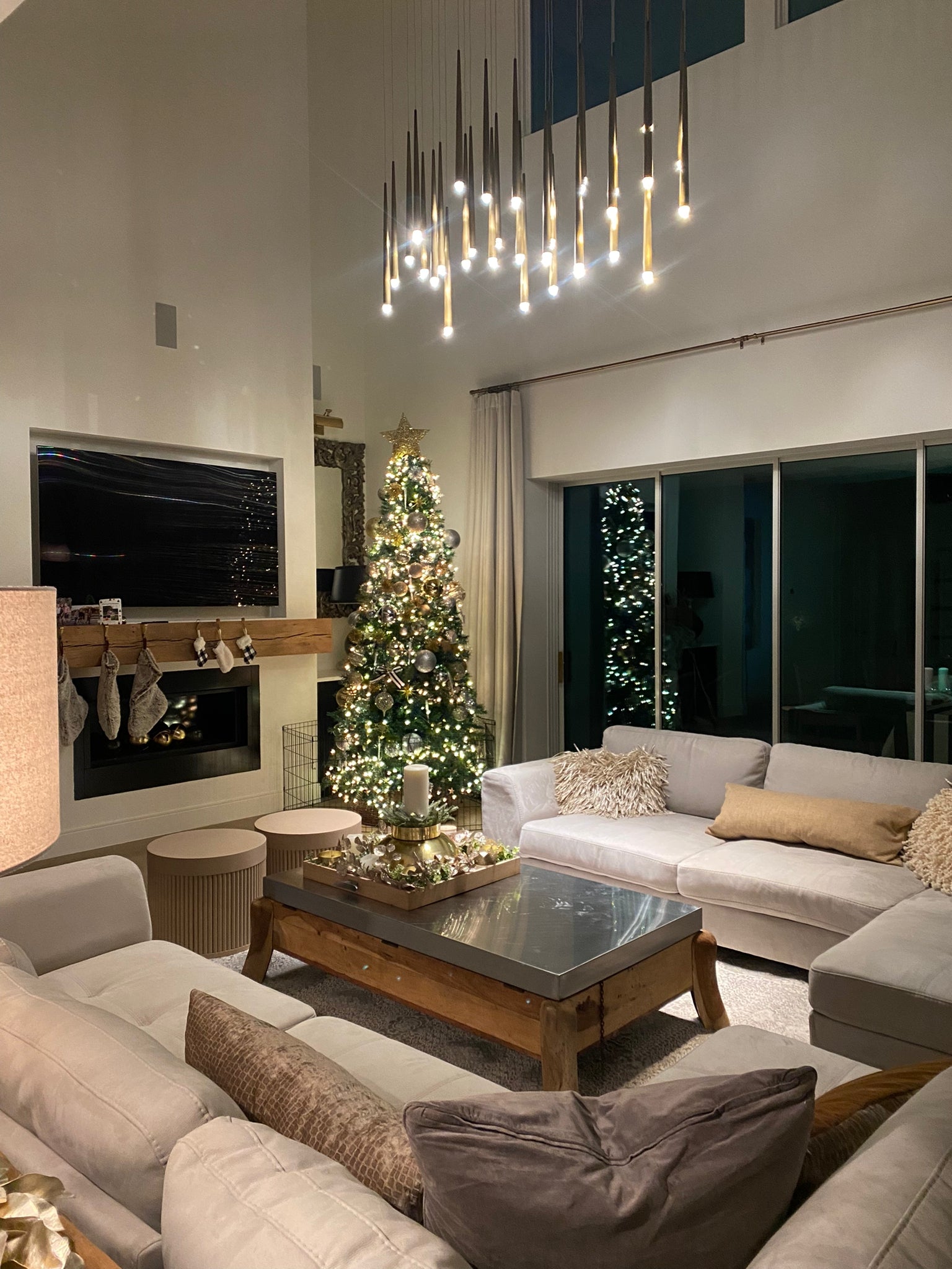 Modern living room with Christmas tree, decorated fireplace, and cozy furniture.