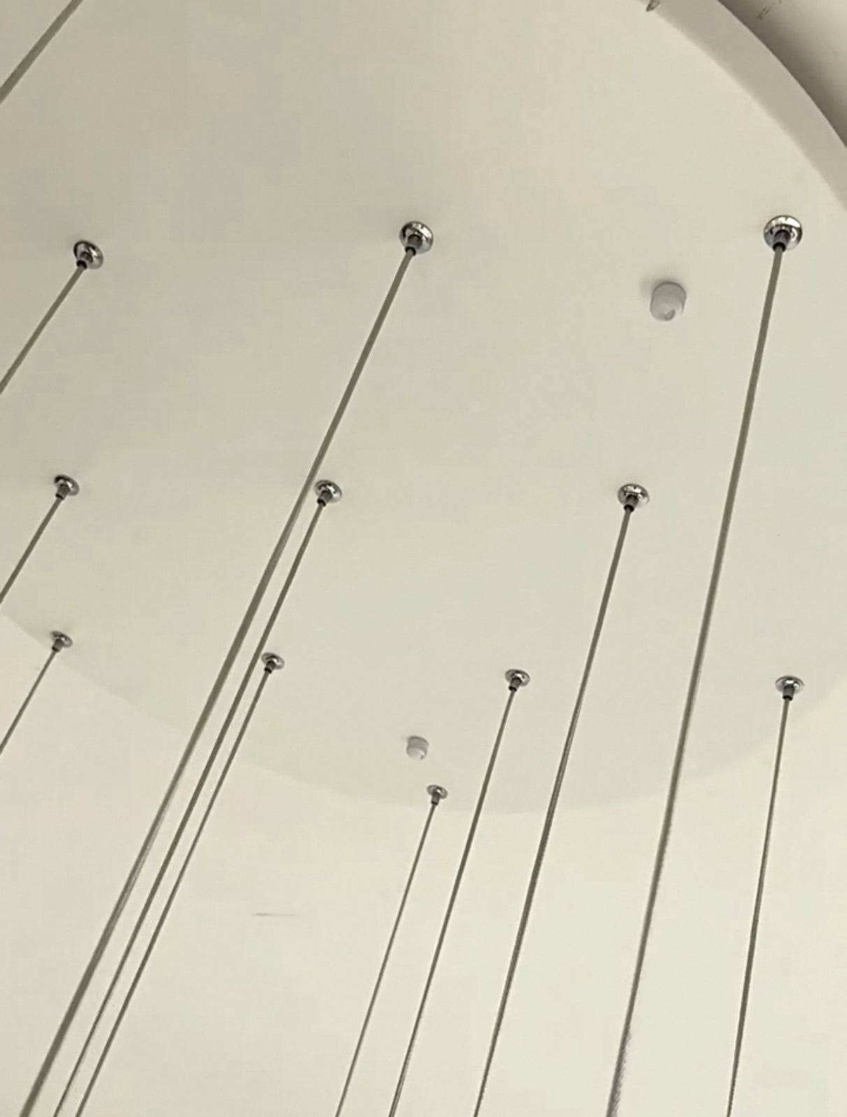 Sleek suspension cables and ceiling mount of the Luminous Waves chandelier.