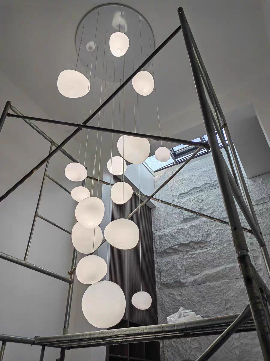 Artistic installation of Aurorae Lighting Pebbles pendant lights in a commercial space