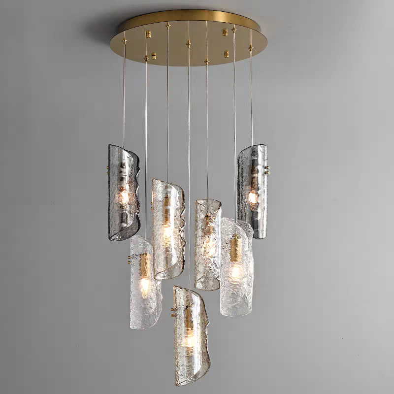 Aurorae Lighting 7-light multi-pendant chandelier featuring artisan textured glass tube shades in clear and smoky grey, elegantly cascading from a round brass-finish canopy.