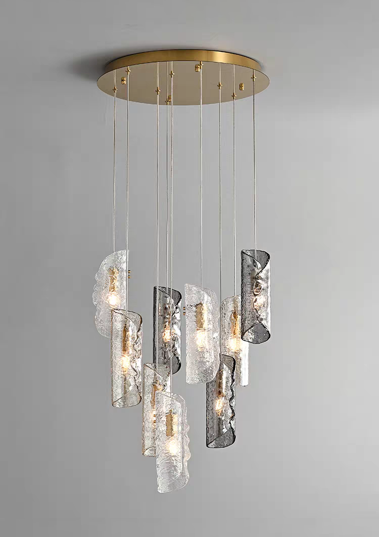 Aurorae Lighting 9-light multi-pendant chandelier, featuring a captivating cascade of artisan textured glass tube shades in clear and smoky grey, all suspended from a round brass canopy.