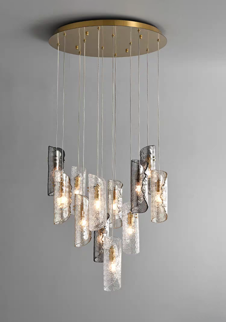 Aurorae Lighting 12-light multi-pendant chandelier, showcasing a dynamic cluster of artisan textured glass tube shades in a mix of clear and smoky grey finishes, all suspended from a sleek round brass canopy.