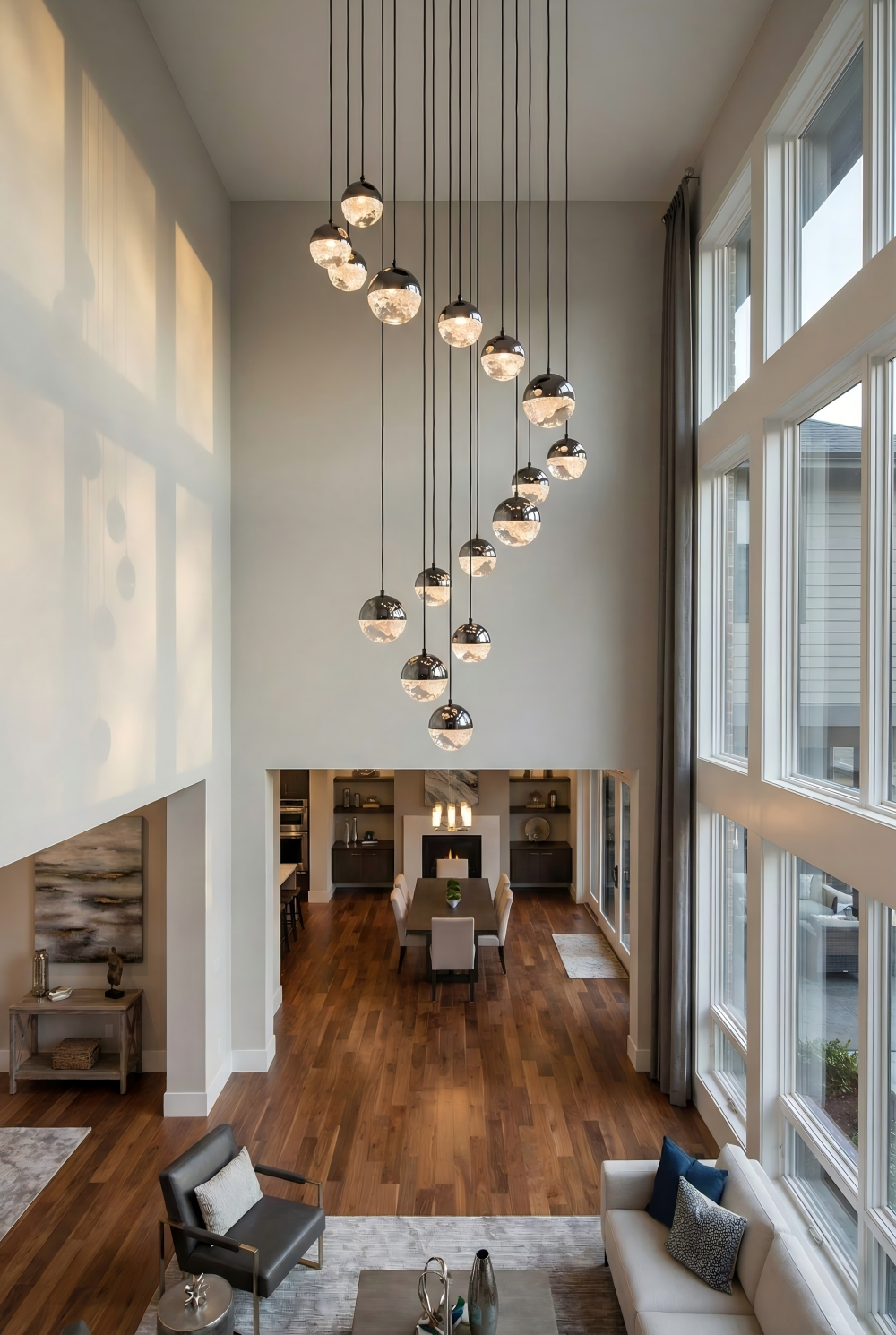 Modern living room with high ceilings, large windows, and a chandelier.