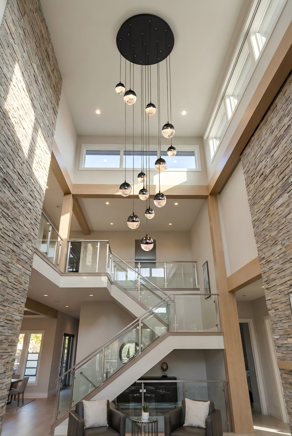 Modern interior with stone walls, glass staircase, and ceiling lights.