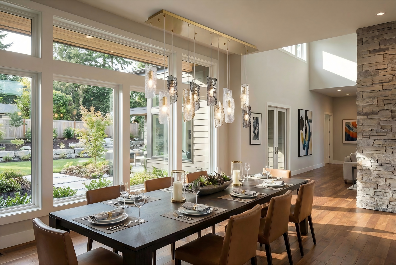 Modern dining room with large windows, stone wall, and decorative lighting.